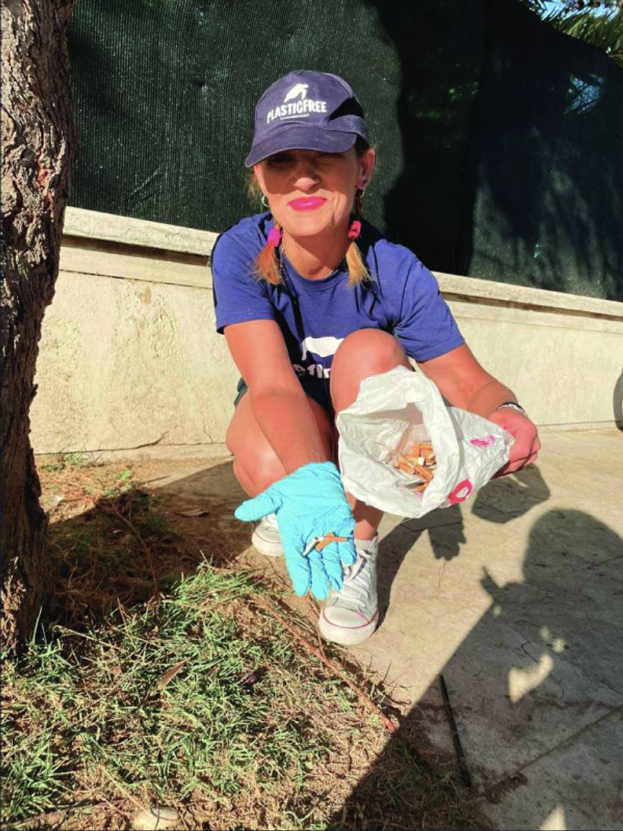 Una donna mostra un sacchetto con le sigarette raccolte lungo una strada